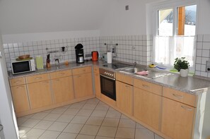 Une cuisine avec des meubles de rangement en bois, un four à micro-ondes, une machine à café et un évier.