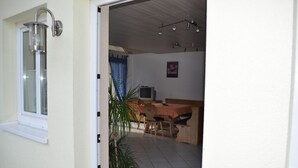 Ein Zimmer mit Esstisch, Stühlen, Fernseher und einer Topfpflanze.