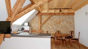 Una cocina rústica con vigas de madera, una pared de piedra y un comedor con sillas de madera.