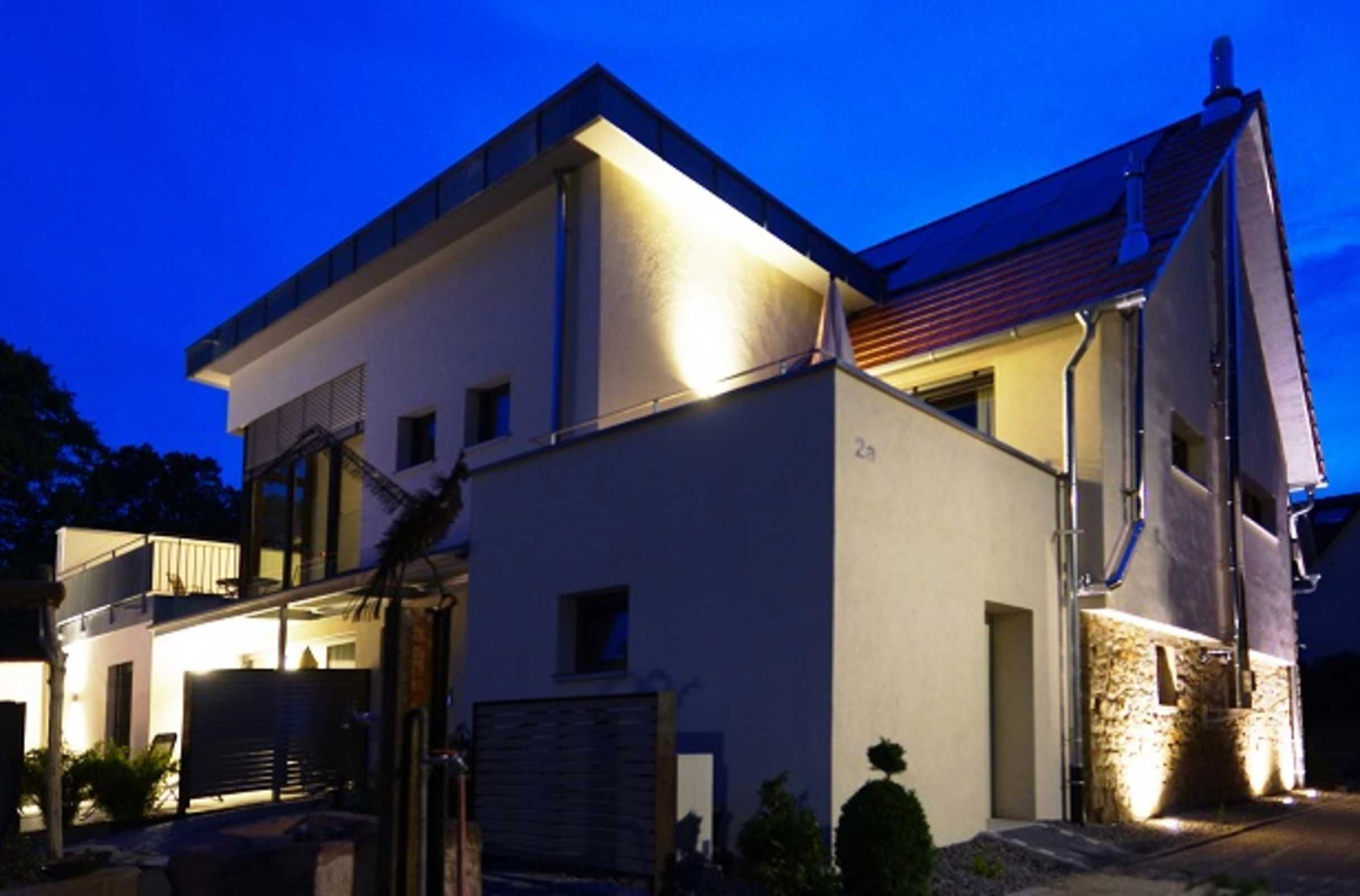 A modern two-story house with a flat roof and a balcony on the upper floor.