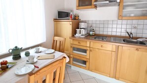 A compact kitchen with wooden cabinets, a microwave, a coffee maker, and a sink. - NR vacation apartment no. 1, 2 persons - Holiday apartment Nain (Bad Dürrheim)