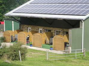 Un edificio con techo de paneles solares, estructura de madera y un área cercada.