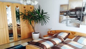 Une chambre à coucher avec un lit, une plante en pot, une armoire et un tableau accroché au mur.