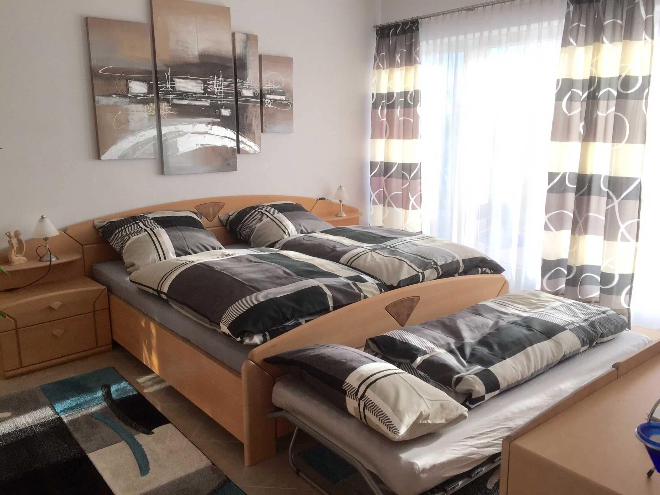 Ein Schlafzimmer mit Bett, Nachttischen, einer Lampe und Kunstwerken an der Wand.