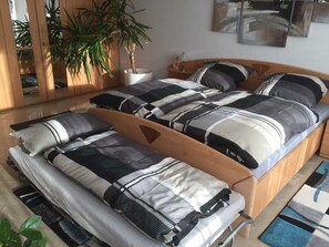 Ein Schlafzimmer mit zwei Betten, einem Holzkopfende, einer Topfpflanze und einem Spiegel.