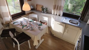 Un comedor con una mesa dispuesta para cuatro, una cocina con fregadero y vistas a zonas verdes.