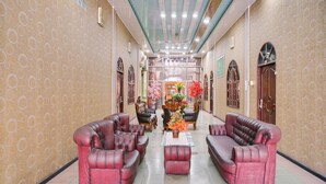 A hallway with two red leather sofas, a central table with a vase of flowers, and a ceiling fan.