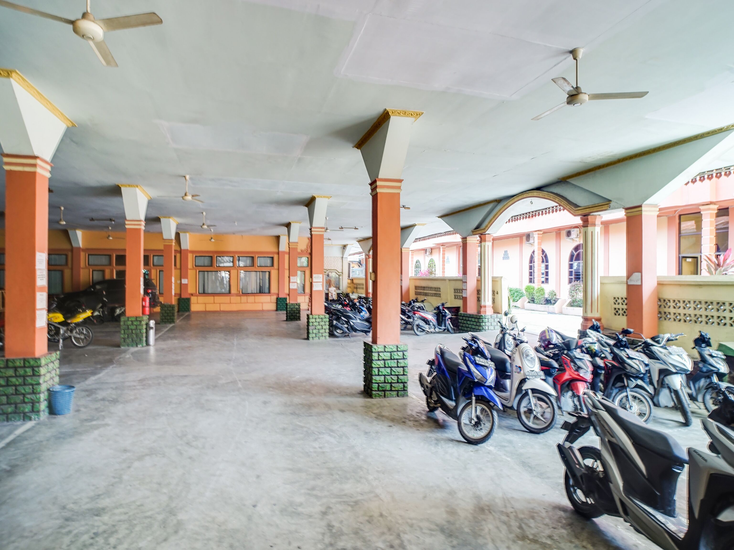 A covered parking area with multiple motorcycles and scooters parked.