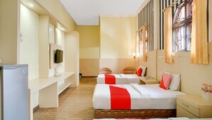 A hotel room with two beds, a television, a refrigerator, and a window with curtains.