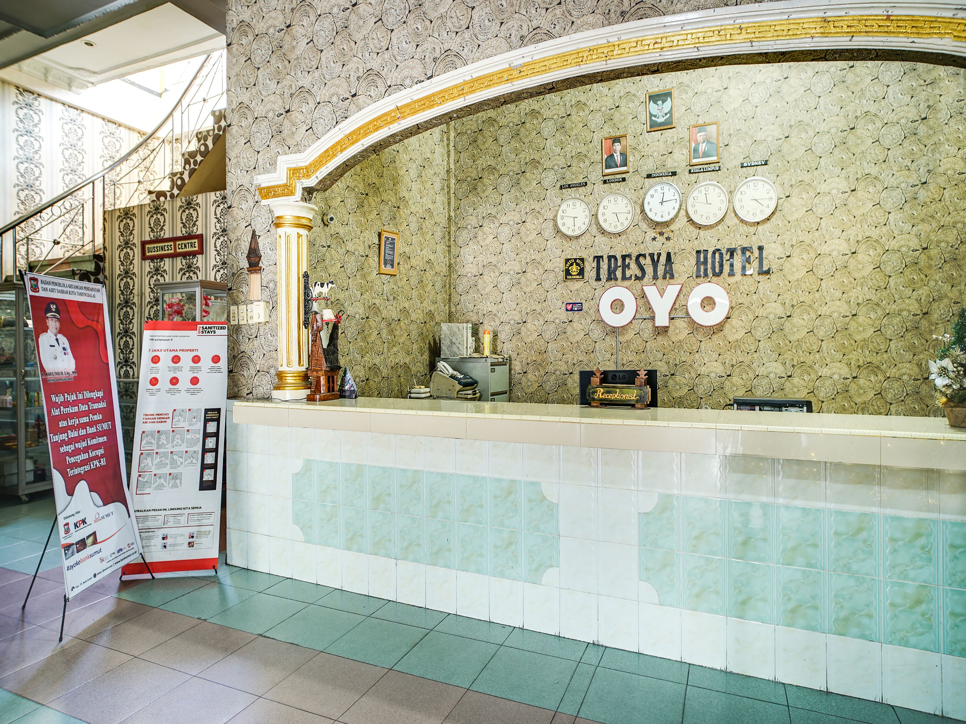 A reception area with a clock, a sign for Tresya Hotel Oyo, and a reception desk.