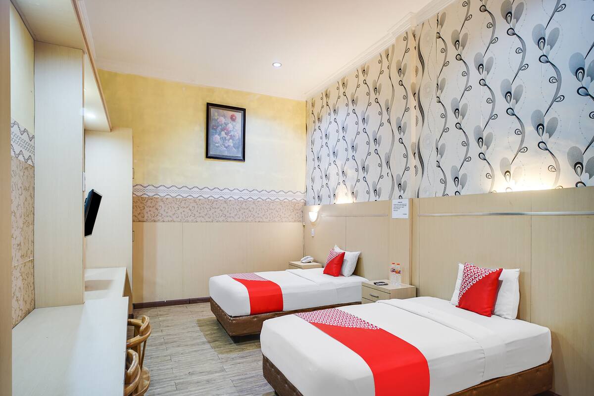Ein Hotelzimmer mit zwei Betten, einem Schreibtisch und einem Stuhl.