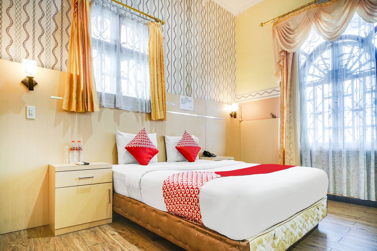 Ein Hotelzimmer mit Bett, Nachttisch und Vorhängen.