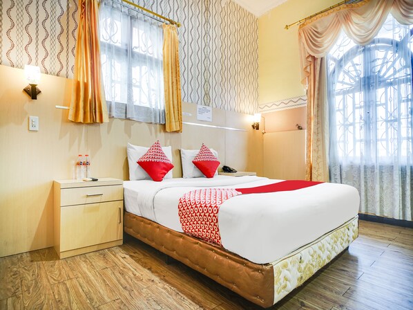 A hotel room with a bed, nightstand, and curtains. - OYO 1140 Hotel Tresya Tanjung Balai (Tanjung Balai)