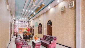 A spacious lobby with a high ceiling, patterned walls, and a seating area with leather sofas and armchairs.