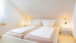 Un dormitorio con dos camas, una mesita de noche y lámparas fijadas a la pared.