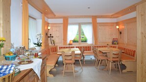 A wooden dining area with benches and chairs, a table with a lamp, and a window with curtains. - Double room 2 with toilet and shower, 1 - 2 persons - Mosertonihof (Elzach)