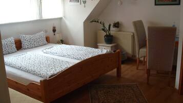 A bedroom with a wooden bed, a chair, a radiator, and a potted plant.
