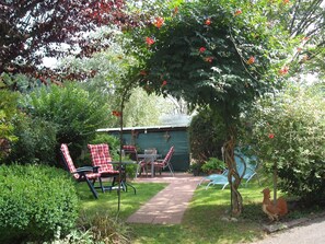 A garden with a patio area, a chicken, and a shed. - Double room with WC and shower (forest side) Das Kleine FEINE - Guesthouse (Ettenheim)