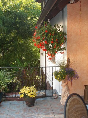 Een balkon met bloempotten en een beeld.