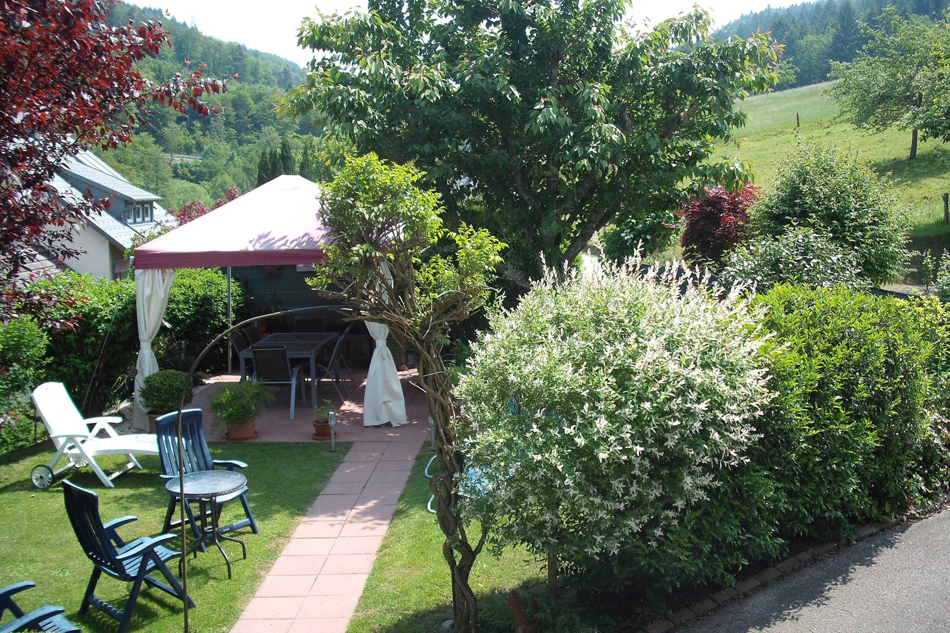 Ein Garten mit Terrasse, Stühlen und einem Tisch.