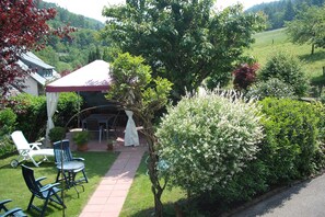 A garden with a patio, chairs, and a table. - Double room with WC and shower (forest side) Das Kleine FEINE - Guesthouse (Ettenheim)
