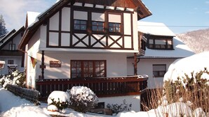 A traditional chalet-style building with a prominent gabled roof, wooden balconies, and a sign indicating a restaurant.