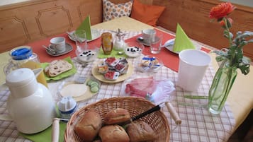 Ein Frühstücksarrangement mit Brot, Gebäck und Getränken auf einer karierten Tischdecke.