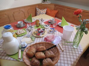 A breakfast setup with bread, pastries, and beverages on a checkered tablecloth. - Double room with WC and shower (forest side) Das Kleine FEINE - Guesthouse (Ettenheim)