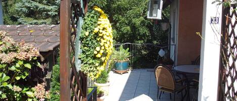 Une terrasse de jardin agrémentée d’une pergola, de plantes en pot et d’une table avec des chaises.