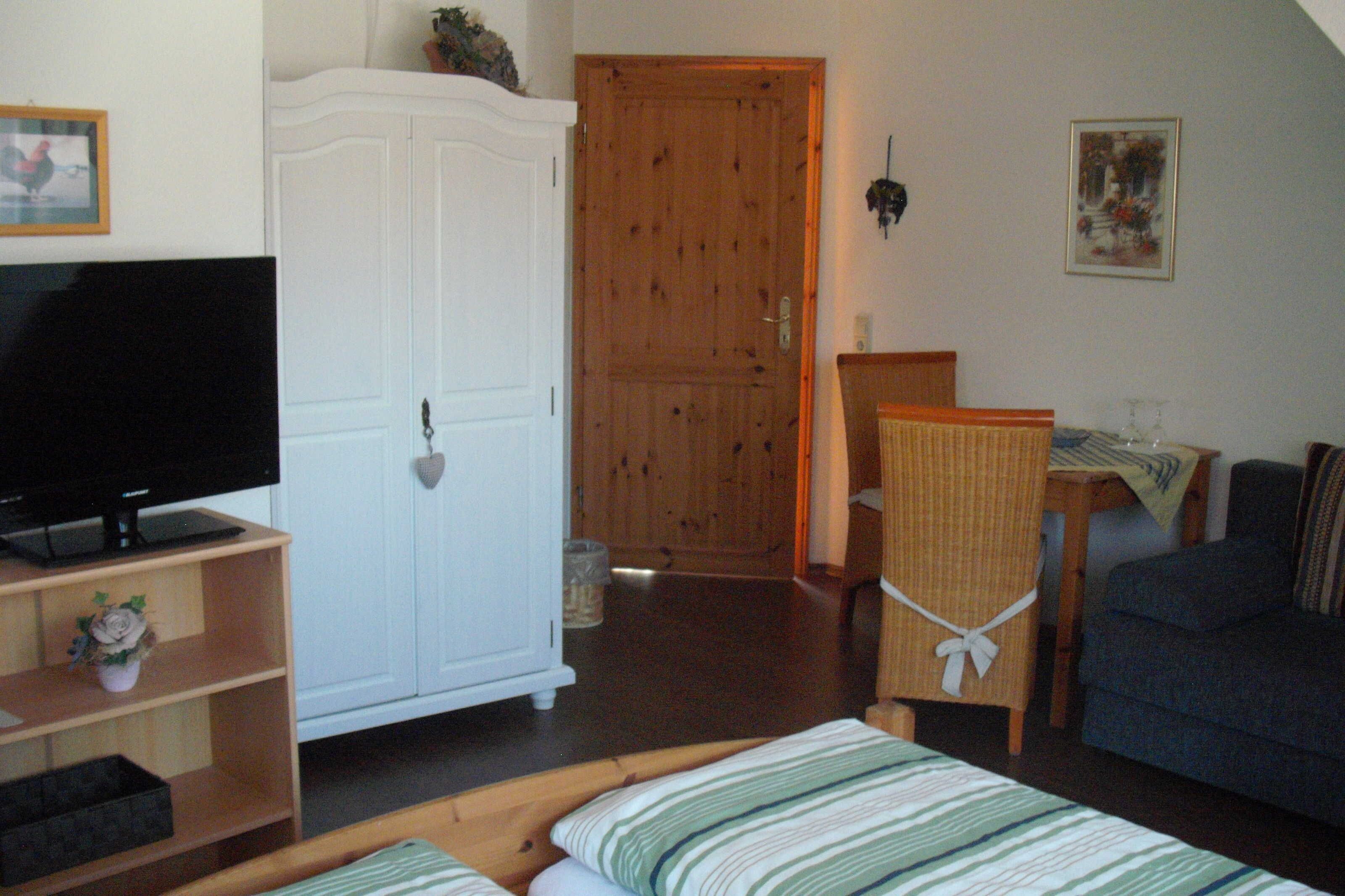 Une pièce comprenant une télévision, une armoire, une table à manger avec des chaises et un canapé.