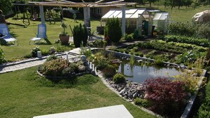 A garden with a pond, seating area, and greenhouse structures. - Vacation apartment Hardtblick 70sqm, 2 bedrooms, max. 4 pers. - Haus Fechtig (Bonndorf im Schwarzwald)