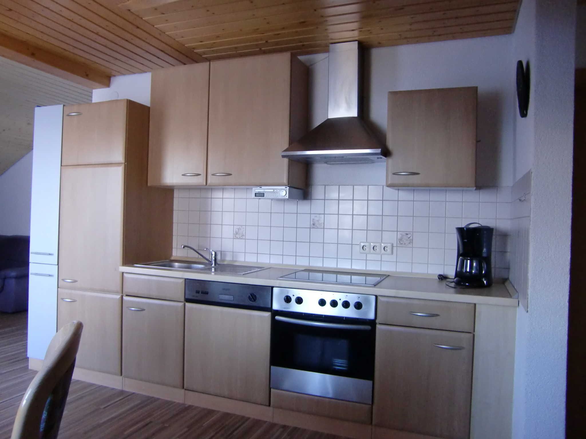 A compact kitchen with wooden cabinets, a stainless steel oven, and a coffee maker.