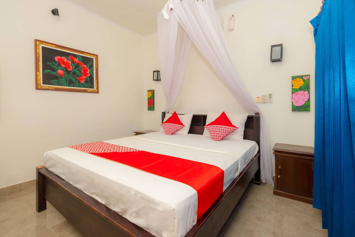 A neatly made bed with a white and red bedspread, a canopy, and a wooden headboard.
