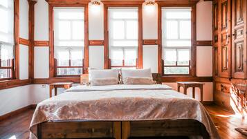 Une chambre à coucher avec un grand lit, une tête de lit en bois et de nombreuses fenêtres.