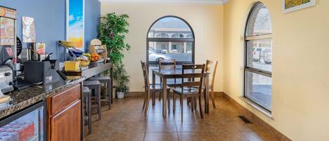 A kitchen with a refrigerator, stove, and sink. There is a dining area with a table and chairs.