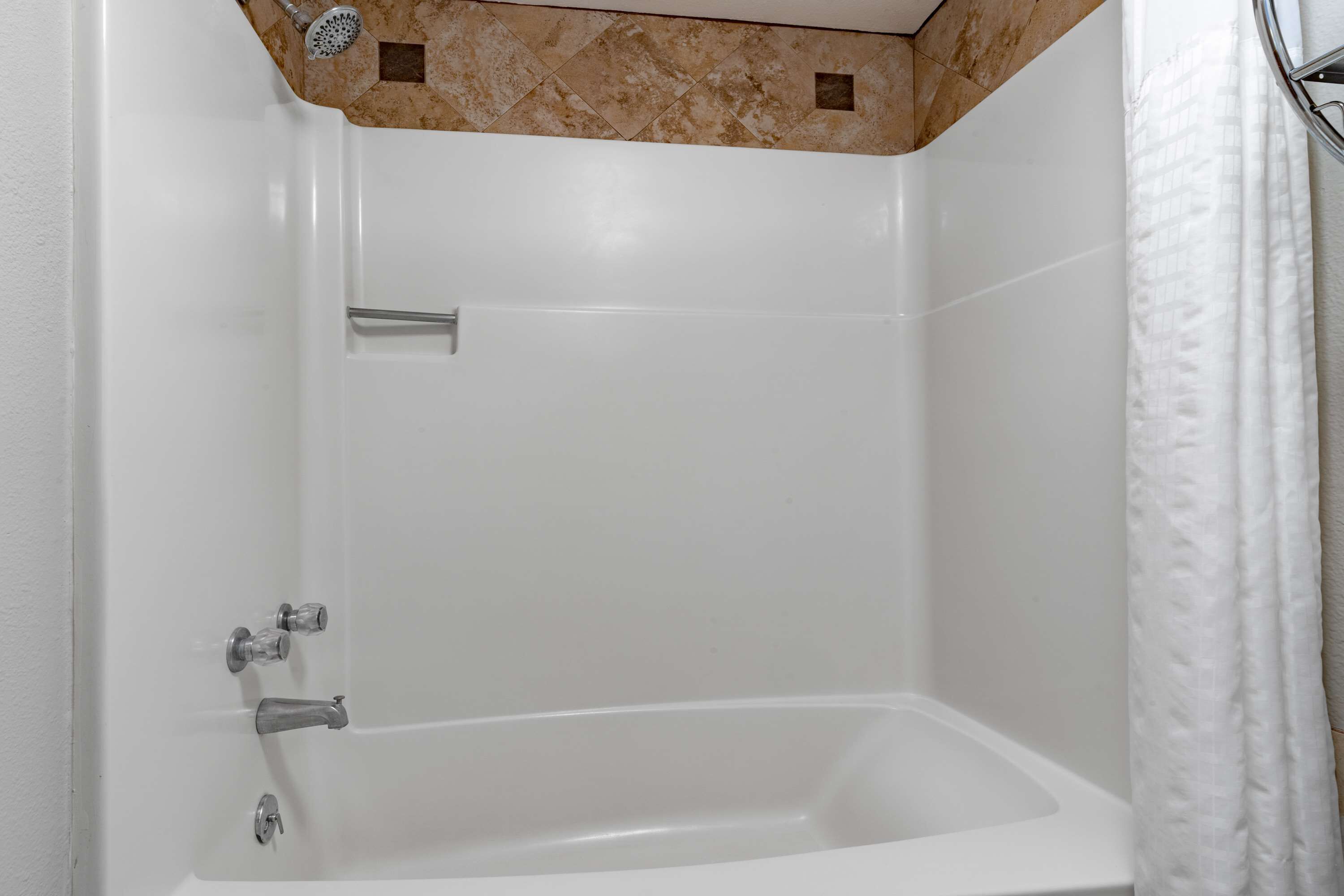 Une baignoire blanche avec un pommeau de douche, un porte-serviettes et un rideau de douche.