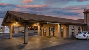 A building with a tiled roof, a covered parking area, and a car parked in front. - Days Inn by Wyndham Winnemucca (Winnemucca)