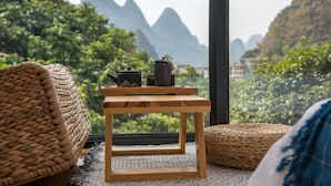 A room with a view of mountains, a wooden table with a teapot, and woven furniture. - Yangshuo Serene Cove Hotel (Guilin)
