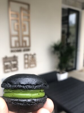 Primer plano de un postre negro y verde sostenido frente a un edificio con un letrero.