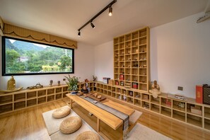Una habitación amplia con un ventanal grande, estanterías de madera y una mesa central.