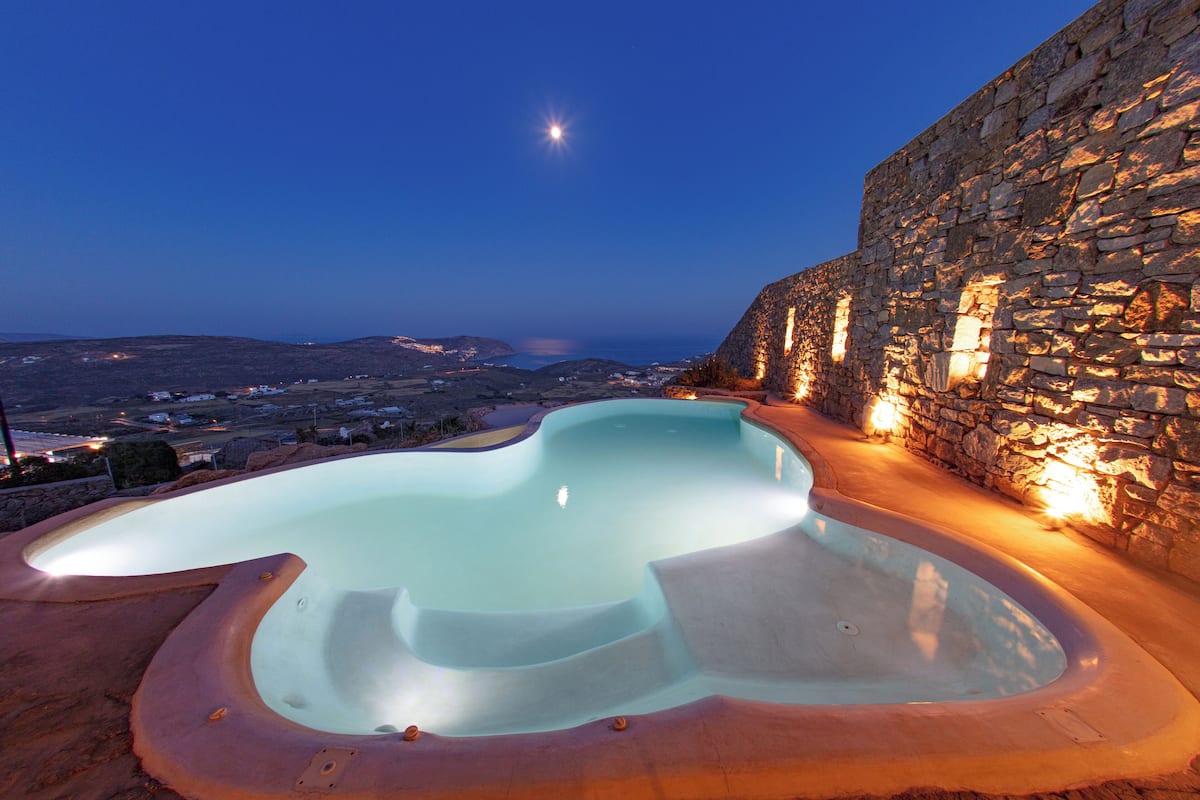 Un jacuzzi con un fondo de pared de piedra y vistas al paisaje.