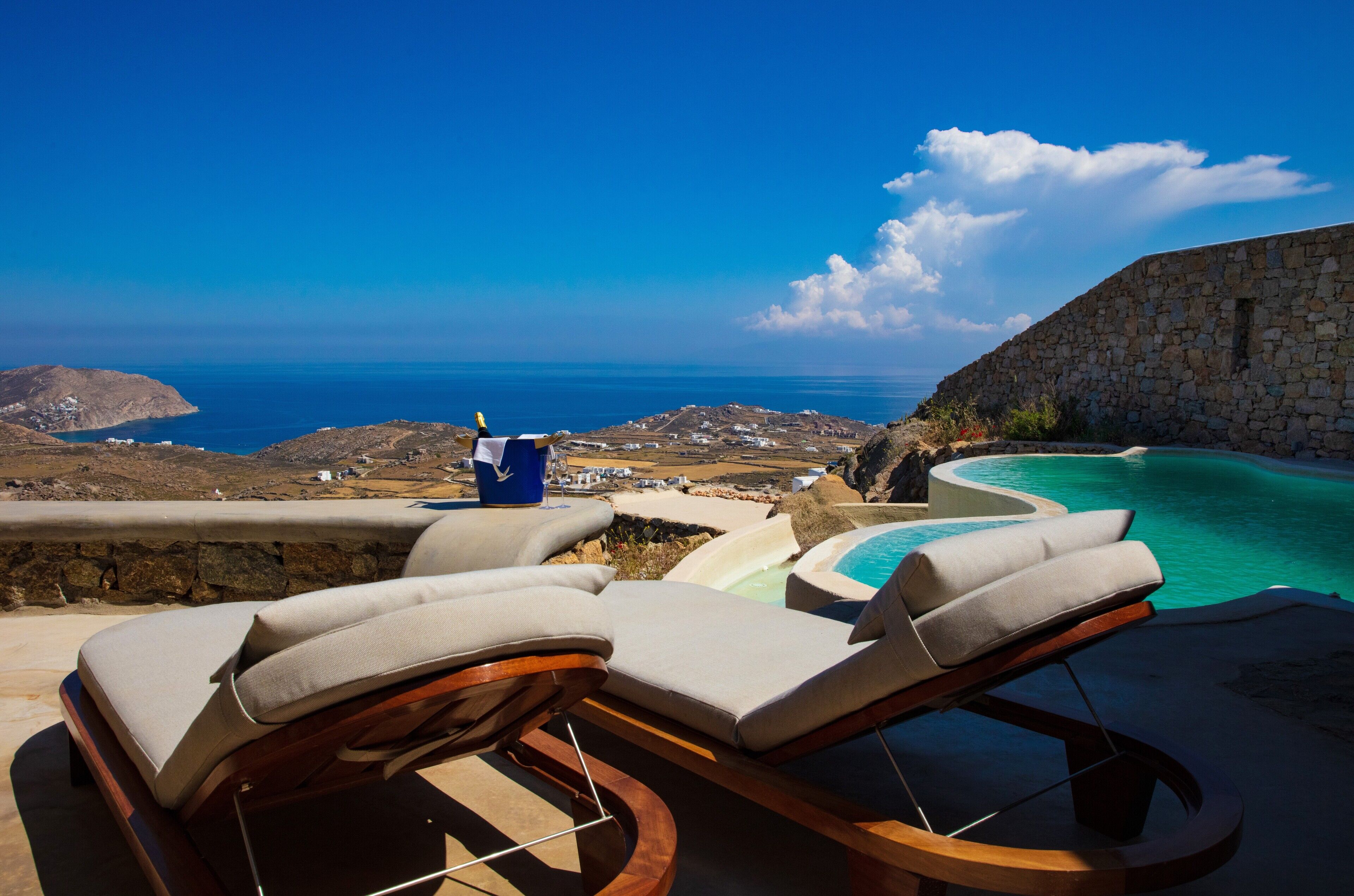 A poolside area with lounge chairs and a view of the ocean.