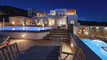 Um resort moderno com piscina, área de estar externa e fachada de pedra.