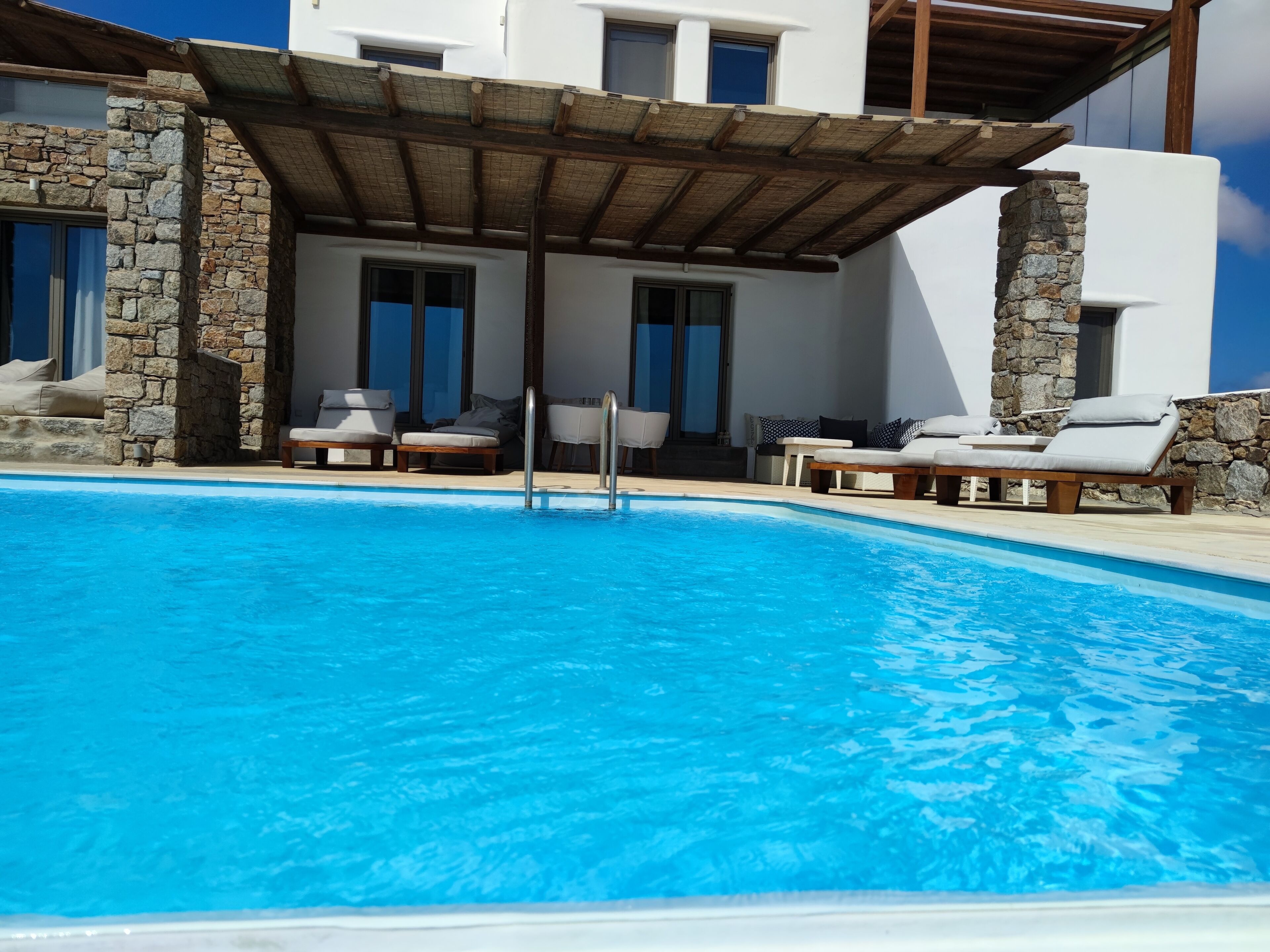 A swimming pool with lounge chairs and a pergola.