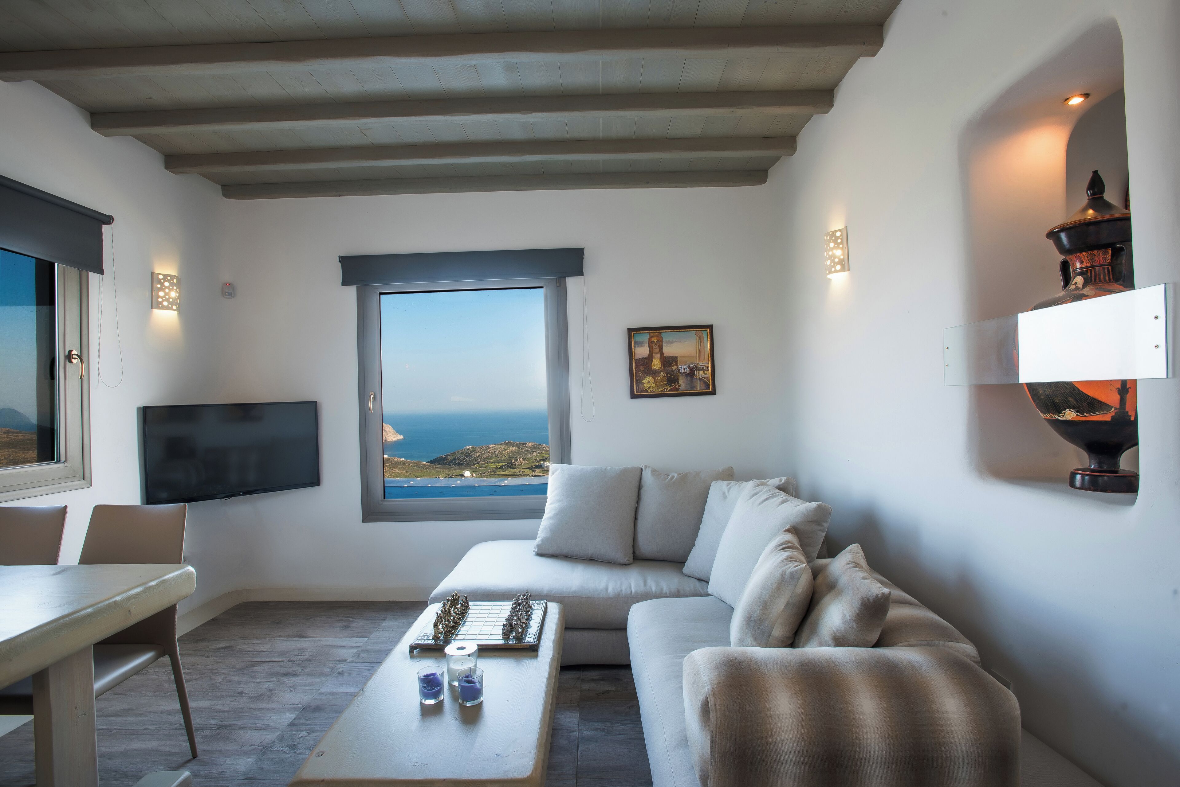 A modern living room with a large window, a flat-screen TV, a sofa, a coffee table, and a dining area.