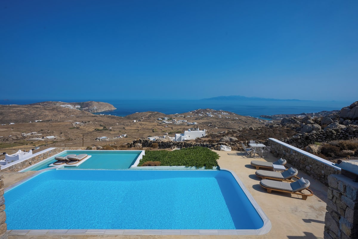 Zona de piscina con sillones de descanso y vistas al mar y al paisaje.