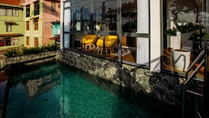 A swimming pool with a tiled floor, surrounded by a stone wall and a glass window. - Tan Villa 2 (Xuan Huong - Da Lat)