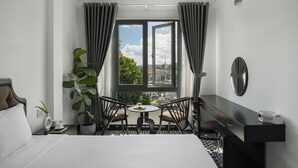 A hotel room with a bed, a desk, a chair, a small table, and a window with curtains. - Tan Villa 2 (Xuan Huong - Da Lat)