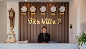 A reception desk with a marble top, a clock, and a sign that reads "Tan Villa." - Tan Villa 2 (Xuan Huong - Da Lat)
