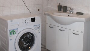 A compact bathroom with a washing machine, a sink, and a mirror. - Studio Zsofia in Budapest (Budapest)